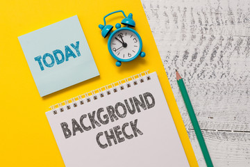 Text sign showing Background Check. Business photo showcasing way to discover issues that could affect your business Spiral notepad paper sheet marker alarm clock retro wooden background