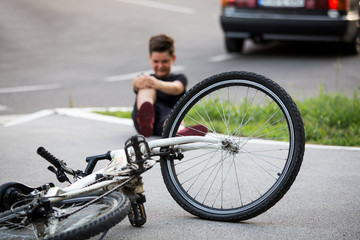 Naklejka premium Teenage boy There is a knee injury, as the bike falls while riding. Kid hurts his leg after falling off his bicycle. Child is learning to ride a bike