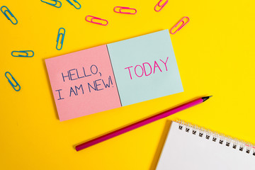 Handwriting text Hello I Am New. Conceptual photo introducing oneself in a group as fresh worker or student Colored square blank sticky spiral notepads pencil clips color background