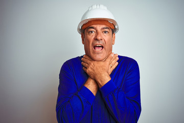 Handsome middle age worker man wearing uniform and helmet over isolated white background shouting and suffocate because painful strangle. Health problem. Asphyxiate and suicide concept.
