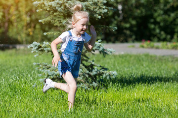 Children run on the green grass holding hands. Girls running around the lawn with grass playing with splashes of water to water plants