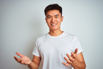 Young asian chinese man wearing t-shirt standing over isolated white background smiling cheerful...
