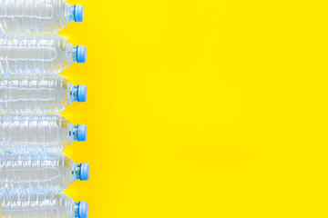 empty plastic bottles for pure water on yellow background top view mock up