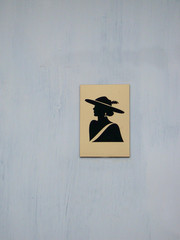 Women's gold and black restroom sign on the grey painted door