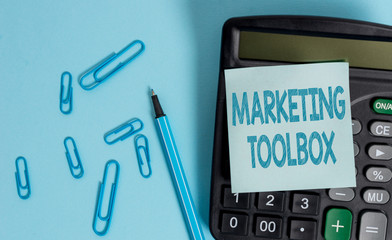 Writing note showing Marketing Toolbox. Business concept for Means in promoting a product or services Automation Electronic calculator blank sticky note clips marker colored background