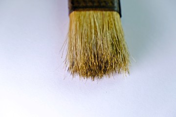 Close up paint brush isolated at the top of frame on white background. Selective focus.