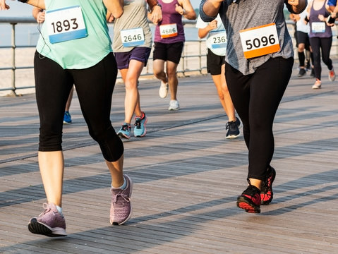 Runners racing on a boardwalk from the waist down