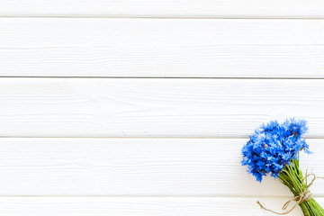 Bouquet of blue cornflowers on white wooden background top view mockup