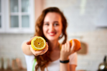 Young happy woman with orange and lemon (citrus) in modern kitchen. Healthy food and Dieting concept. Loosing Weight