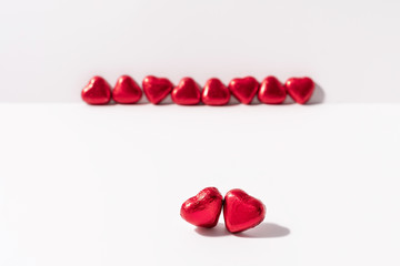 Heart shape chocolates wrapped in red foil on white background. Valentines day gift. Love and parting concept. Copy space.