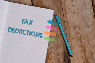 Conceptual hand writing showing Tax Deductions. Concept meaning an amount or cost that subtracted from someone s is income Striped notebook colored arrow banners ballpoint wooden background