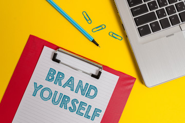 Word writing text Brand Yourself. Business photo showcasing Develop a unique professional identity Personal product Open laptop clipboard blank paper sheet marker clips colored background