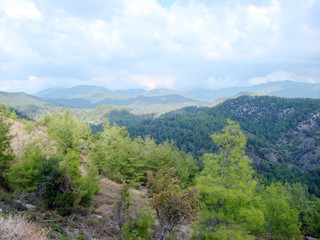 Fototapeta premium Landscape above mountain ranges decorated with colorful autumn forest under the rays of the evening sun against the background of clouds, descending to the top of the mountains.