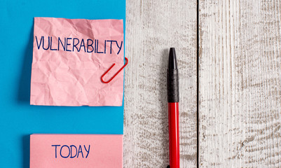 Handwriting text Vulnerability. Conceptual photo State of being exposed to the possibility of being attacked Wrinkle paper and cardboard plus stationary placed above wooden background