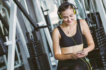 Active girl using smartphone in fitness gym. Young woman workout in gym healthy lifestyle. Young woman using phone in gym. Change for health concept.