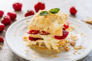 Portion of Napoleon Cake with Strawberry Closeup. Custard Cream Dessert with Red Ripe Berry and Decorated Green Leaves on Top. Bakery Tasty Sweet Dish and Fresh Gourmet Breakfast Pie