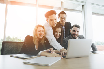 Businessman presenting to colleagues at a meeting.Successful team leader and business owner leading informal in-house business meeting. Businessman working on laptop in foreground.