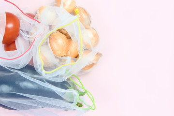 Fresh vegetables in grocery bags on a pink background, copy space