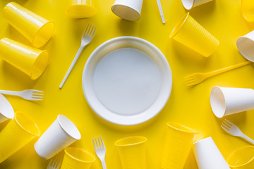 Disposable white picnic utensils for recycling on yellow. Top view. Flat lay.