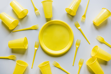 Disposable yellow picnic utensils on grey. Environment eco friendly discarded plastic garbage collection for recycle concept.Top view. Flat lay. Pattern.
