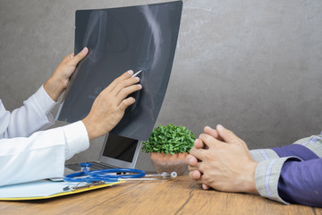 Asian male doctor holding x-ray with patient.