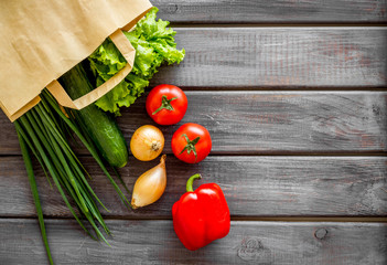 Buying fresh vegetables in paper bag on wooden background top view copyspace