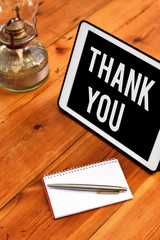 Handwriting text writing Thank You. Conceptual photo a polite expression used when acknowledging a gift or service Writing equipments placed next to gadget plus a classic vintage lantern