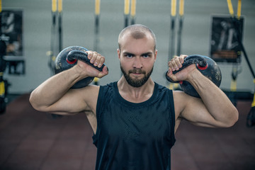 Cross fit athlete exercising with a kettlebell at the gym. Handsome man doing functional training....