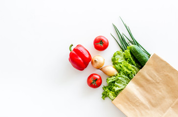 Buying fresh vegetables in paper bag on white background top view copyspace