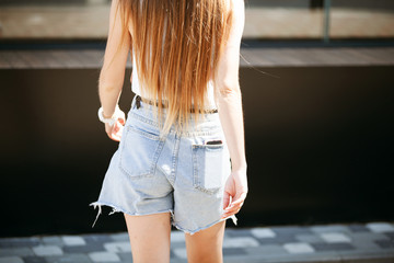 Sexy back of a girl in denim shorts on the street.