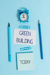 Writing note showing Green Building. Business concept for A structure that is environmentally responsible Sustainable Alarm clock squared paper sheet notepad markers colored background