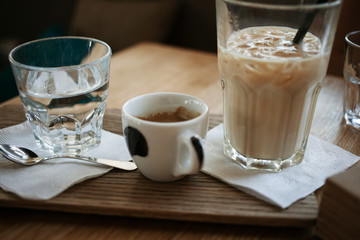 Morning cofee lifestyle. Cup of espresso and a glass of ice latte standing on the wooden desk.