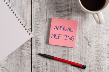 Handwriting text Annual Meeting. Conceptual photo yearly meeting of the general membership of an organization Stationary placed next to a cup of black coffee above the wooden table