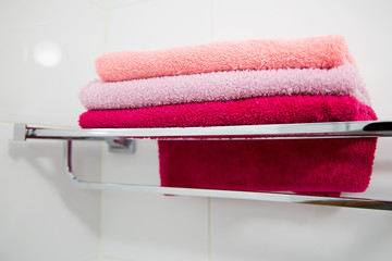 A stack of multi-colored towels on a metal shelf. Horizontally.