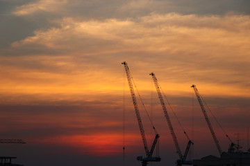 Cranes construction site with silhouette development beautiful  sunset background