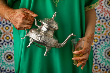  Moroccan woman with henna painted hands pouring tea