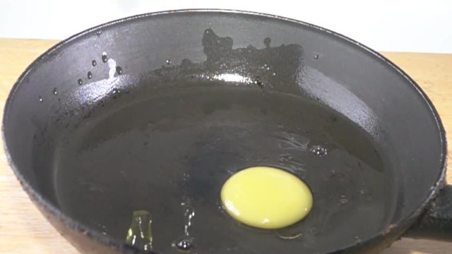 Broken eggs fall into the pan from a height and flow over the oil surface. Breakfast at half of the world's population, Super slow motion 1000 fps
