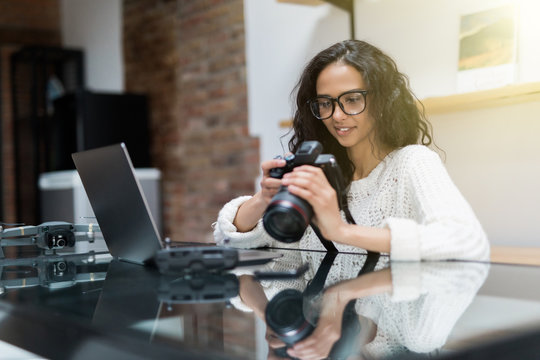 Female photographer sitting on the desk with laptop at home