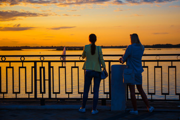 Fototapeta na wymiar Two friends admire the sunset on the city embankment.