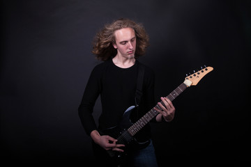 Obraz premium Young caucasian adult playing guitar in the studio