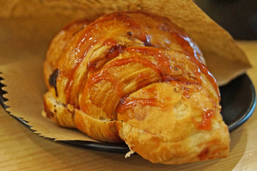 Croissants with a golden crust with chocolate and cherry confiture on a black saucer