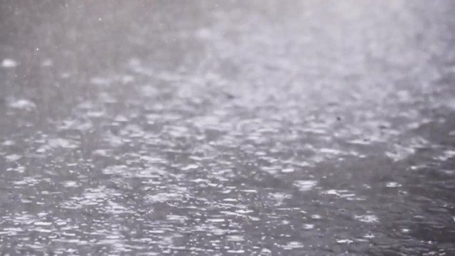 コンクリートの地面に打ちつける雨のイメージ