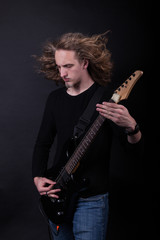 Young caucasian adult playing guitar in the studio