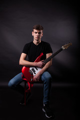 Obraz premium Young caucasian adult posing in the studio with rock guitar