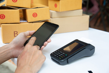 businessman hand using the card machine to pay the goods before packing in the box to deliver to the customer