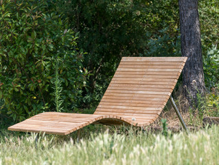 Wooden lounger on a meadow in the sunshine