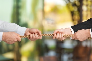 Business people pulling rope in opposite directions at office