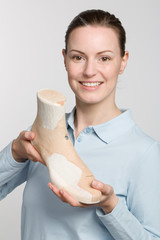 proud female orthopedic shoemaker holds a handmade wooden last