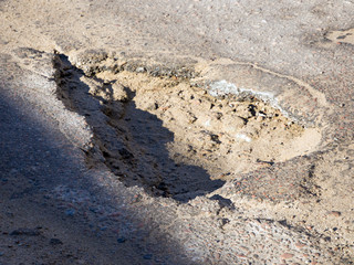 Large and deep pit on an asphalt road