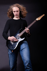 Obraz premium Young caucasian adult playing guitar in the studio